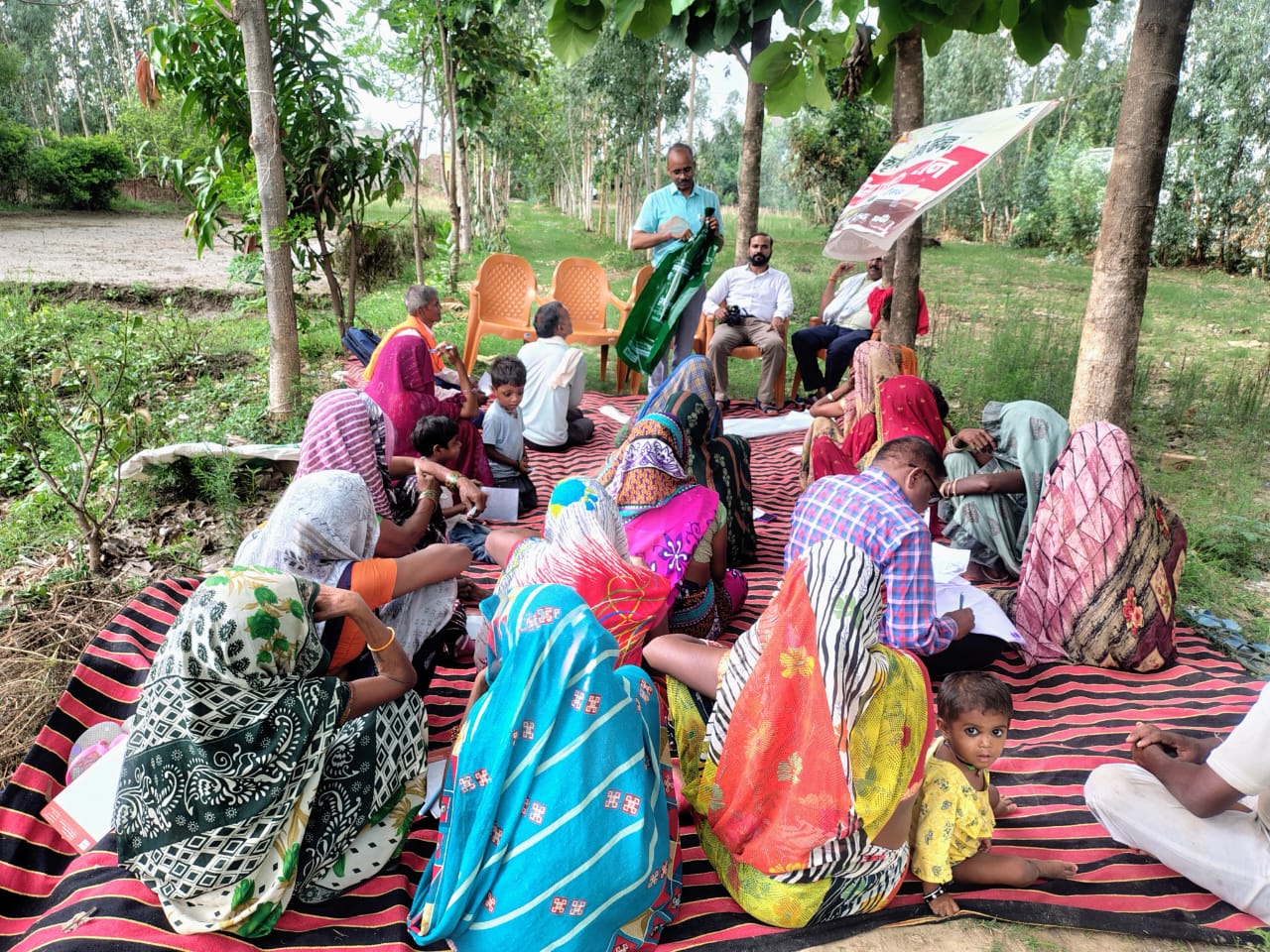 KVK scientists speaking with women farmers seated on a mat at a village meeting in Chausarh